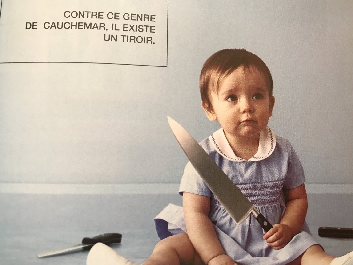 A vintage advertisement of a baby holding a large kitchen knife
