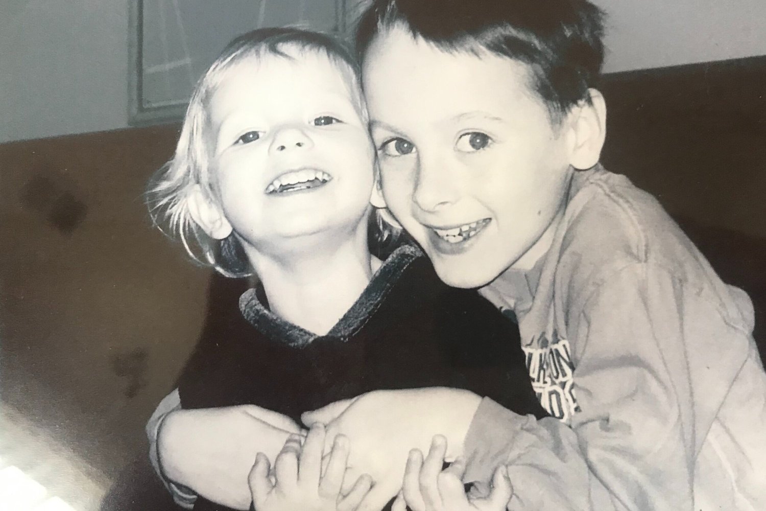 Two smiling children hugging, in a black-and-white photograph